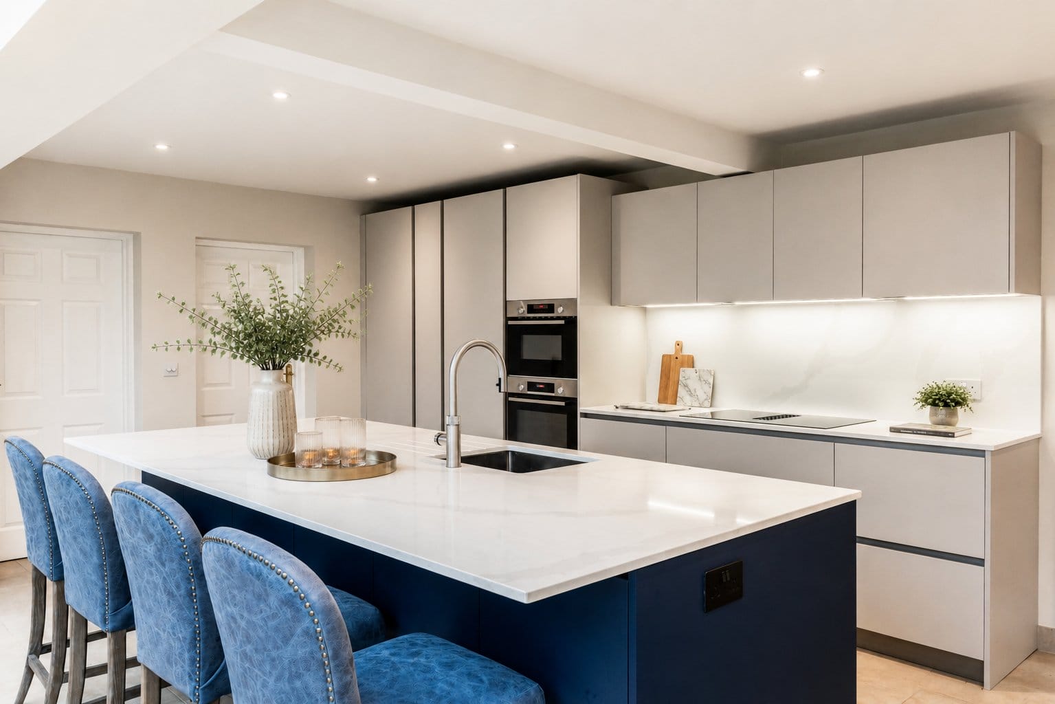 Bright contemporary shaker kitchen with cream cabinetry, integrated appliances, quartz worktops and soft under-cabinet lighting.