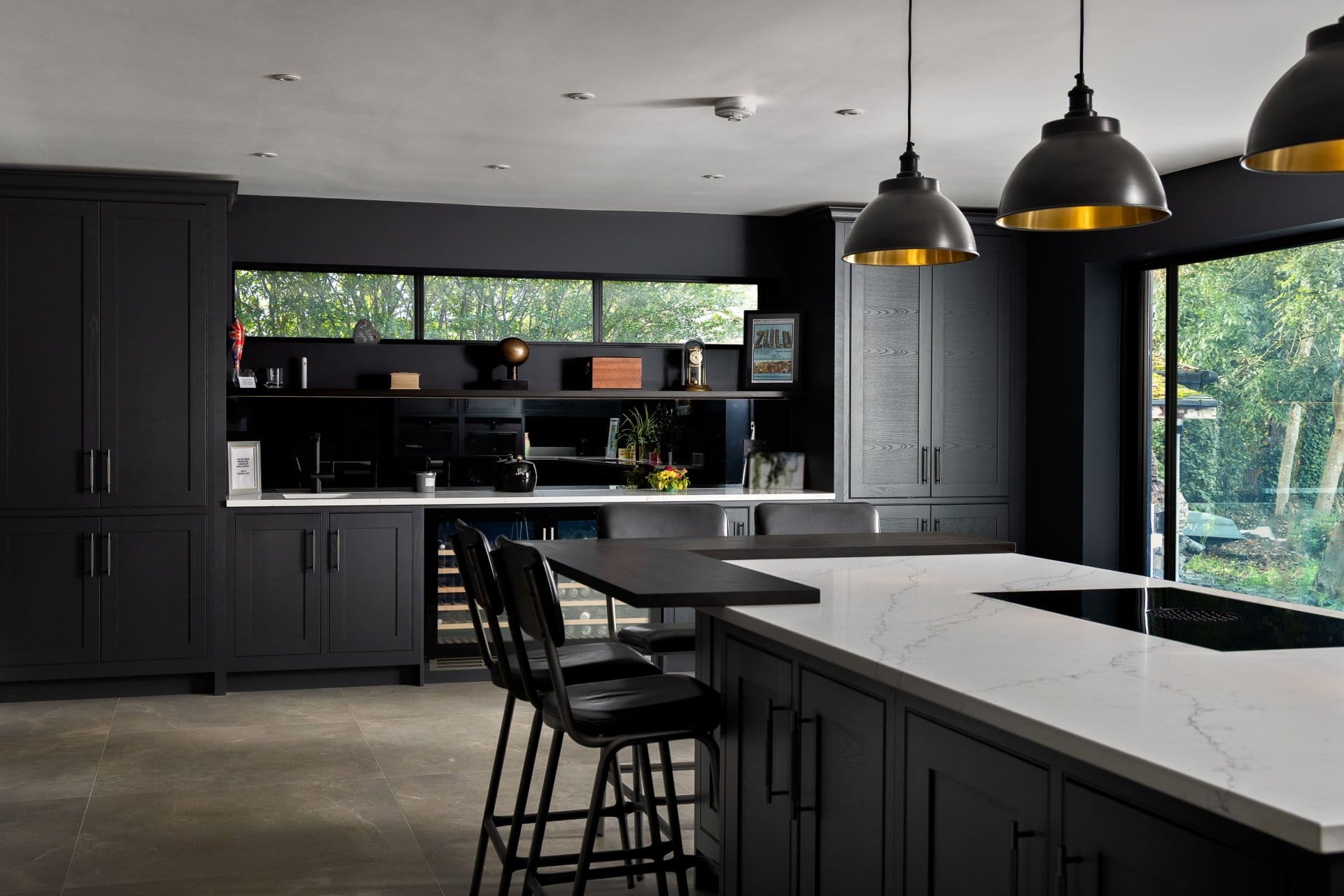 Artizan Interiors contemporary dark kitchen with a large marble island, black cabinetry, pendant lighting and open-plan living design.